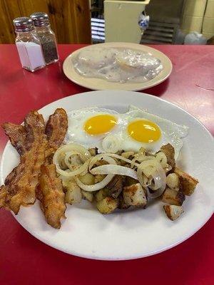 Bacon, sunny side up done perfectly, lots of onions in those home fries and sausage gravy the way you want it.