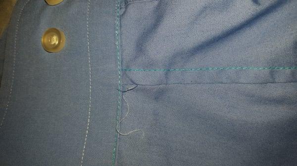 The teal color is the thread used at the tailors,  the lighter color is the original.  Note the loose threads.