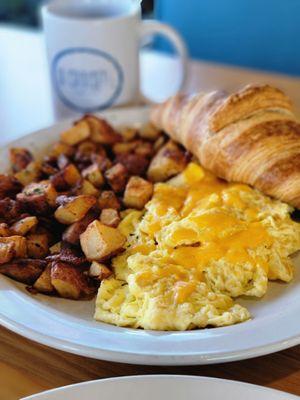 Scrambled eggs with cheese and home fries.