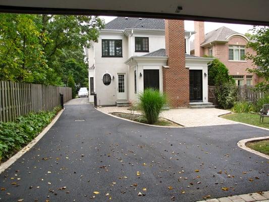 Asphalt driveway paving with brick border and stone patio