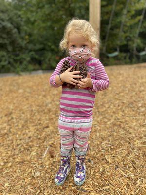 Early Childhood student collecting pine cones on the playground.