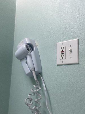 Broken hairdryer that's hanging off the wall