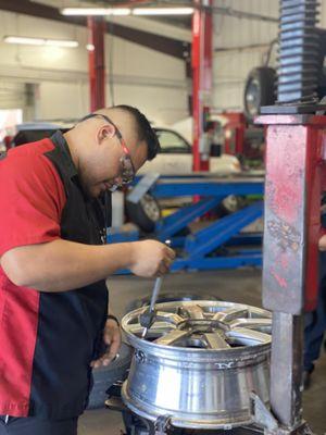 Josh Sablan focusing on  replacing a tire and changing out the valve stem.