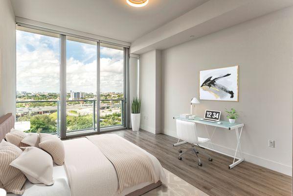 Spacious bedroom with hardwood style plank flooring and floor to ceiling windows with private balcony at Lantower River Landing.