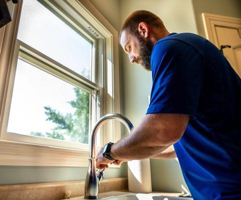 A Covenant Plumbing plumber stands confidently above a sink, ready to tackle any plumbing issue...