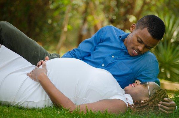 Baby-moon - A couple, a pregnant woman and a man  lying on the ground looking into each other's eyes.