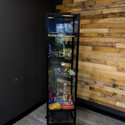 Glass display case with water pipes, bubblers, chillums, rolling trays, and more