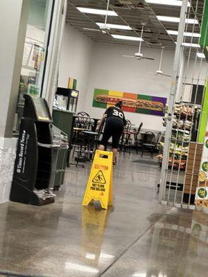 Employee finishing cleaning up with gate nearly closed, during business hours.