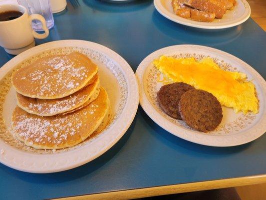 Scrambled eggs with cheese, pork sausage patties and pancakes.