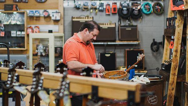 Aaron working on a banjo in the showroom.