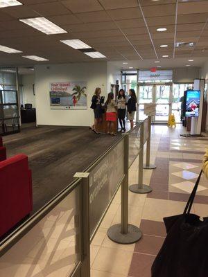 Four employees stand around while 12 people wait for 2 tellers.