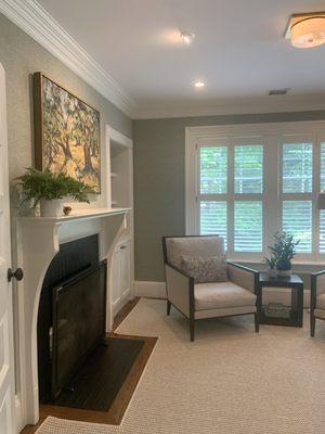 A fully transformed office space complete with built in bar, grasscloth walls, and handsome Hunter Douglas shutters.