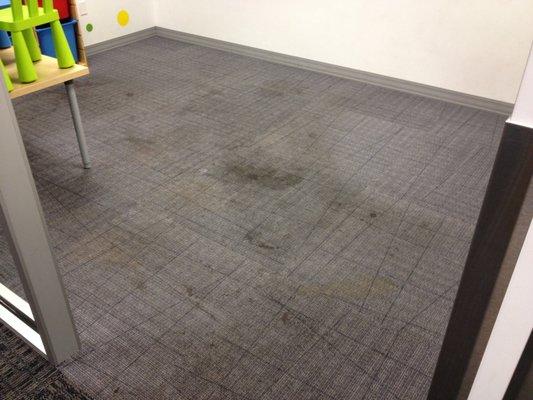 Play room at a business with soda stained dirty carpet.