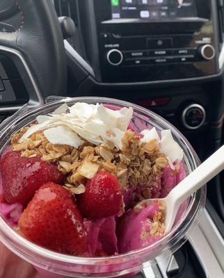 dragonfruit smoothie bowl with strawberries, granola, and coconut flakes