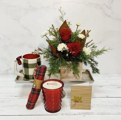 A Simpatico candle with 100 hour burn time, a festive mug, plaid dish towel, hand written greeting card, and a petite seasonal arrangement.