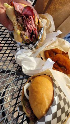 Pastrami burger, onion rings, and cheeseburger