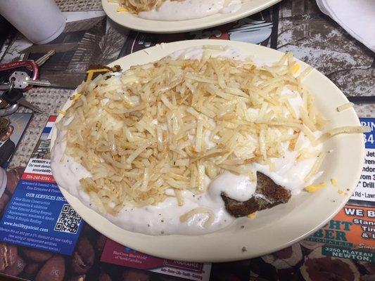 Garbage plate with biscuits, over-medium eggs, livermush, cheddar cheese, country gravy, and hashbrowns.