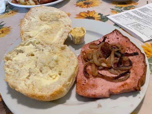 Fried Fleischkäse with grilled onions and a buttered brötchen. You can add a fried egg to make it a breakfast sandwich.