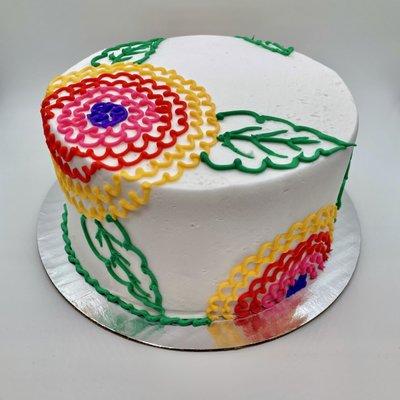 Flowers with an embroidered vibe on a white cake with white buttercream icing.