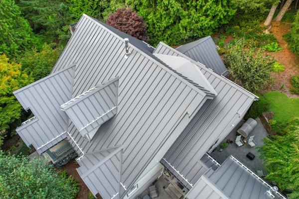 An aerial view showcasing the intricate design and durability of an aesthetic modern gray metal roof on a suburban home.