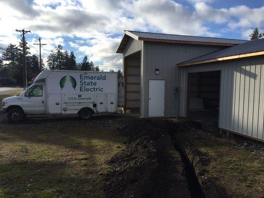 Installing a new 200-amp service to a detached shop. Trenching for new service conductors to electrical meter on the right.