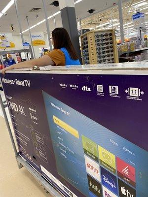 Sales associate assisting with the second tv with open box,