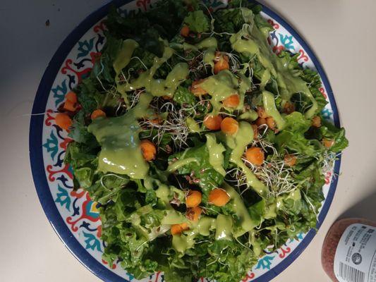 A healthy green salad with ranch and avocado salad dressing