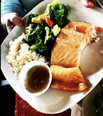 Salmon cooked medium well with house sauce on the side. Fresh steamed vegetables and rice.