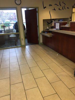 Teller at the end,that you can not see.(maybe for people who need special assistance) if so she should stand when calling the next customer