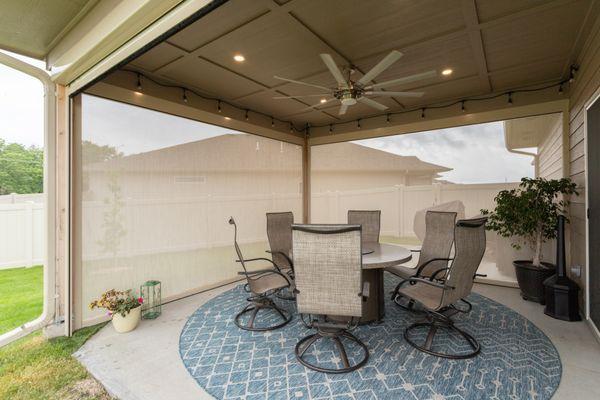 Motorized exterior screens close in this outdoor patio to block from wind, bugs, sun, and nosy neighbors.