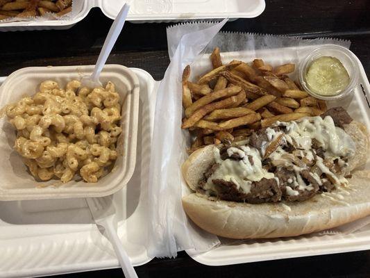 Cheesesteak with fries and pickle chips and an added side of Mac and cheese