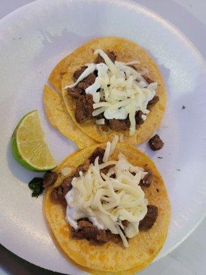 Tacos with asada, cheese and sour cream