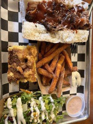 Pulled pork sandwich with regular and spicy BBQ sauces, homemade cornbread, sweet potato fries, salad, ranch, and fry sauce.