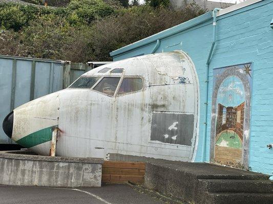 Airplane nose projecting out of the side of a building