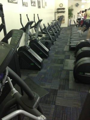 Lots of cardio machines - bikes and in front of these are treadmills & steppers