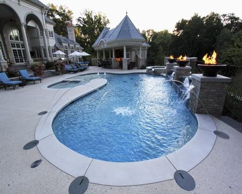 A custom gunite in ground swimming pool with spill over hot tub, fire bowls, deck jets and a kiddie area.