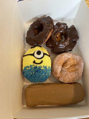 Two chocolate old fashioned donuts, a Minion donut, a jelly donut, and a maple bar. They smell so good!