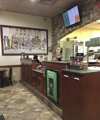 Counter with history of Marco's Pizza on the wall.