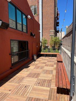 Patio with bamboo, wood benches, clear view into the gym, speakers, heat lamps, and....vibes!