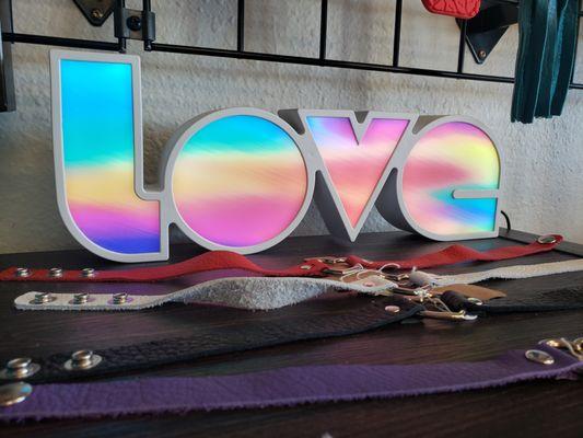 Quality leather collars displayed in front of a light-up sign that says 'Love'.