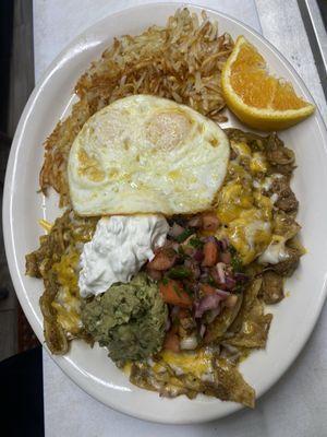 Chilaquiles en salsa de puerco verde , chile verde , with 2 over median eggs and hash browns with pico de Gallo ,guacamole and sour cream