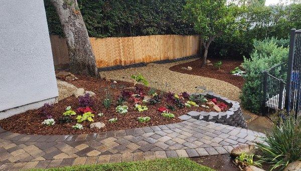 New planting, garden block wall, mulch, and gravel for a low maintenance, low water, yet beautiful backyard.