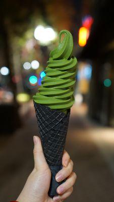 matcha soft serve in a black charcoal waffle cone