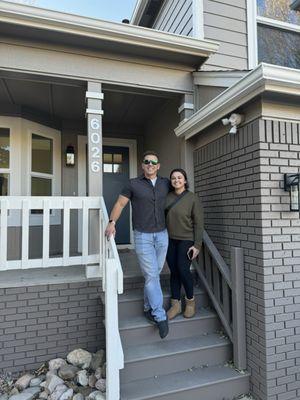 2 people standing on the porch of their new home.