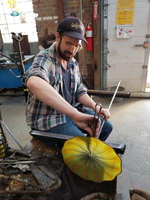 Lead glassblower, Eli Zilke, works on a large commissioned installation