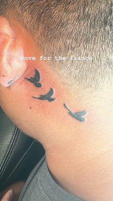 Flying dove tattoo behind the ear