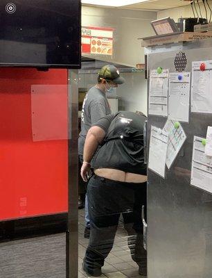 Employees preparing pizza in kitchen