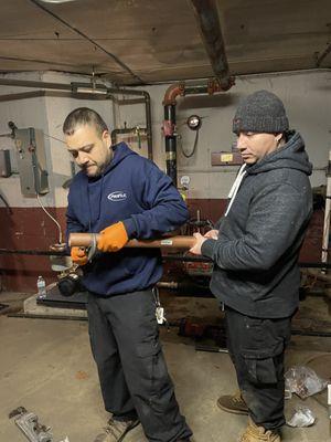 Our certified plumbers working together on a pipe repair job.