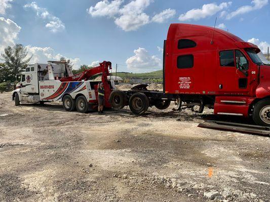 A tow truck towing a junk truck