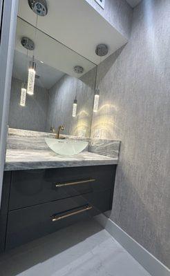 Floating sink base with a slab door style, larfe hardware and glass vessel sink.  This is a beautiful powder room,